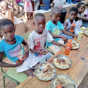 Niños y niñas comiendo un plato de arroz con pollo
